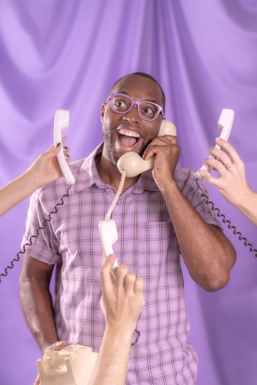 Man happily talking on multiple old phones